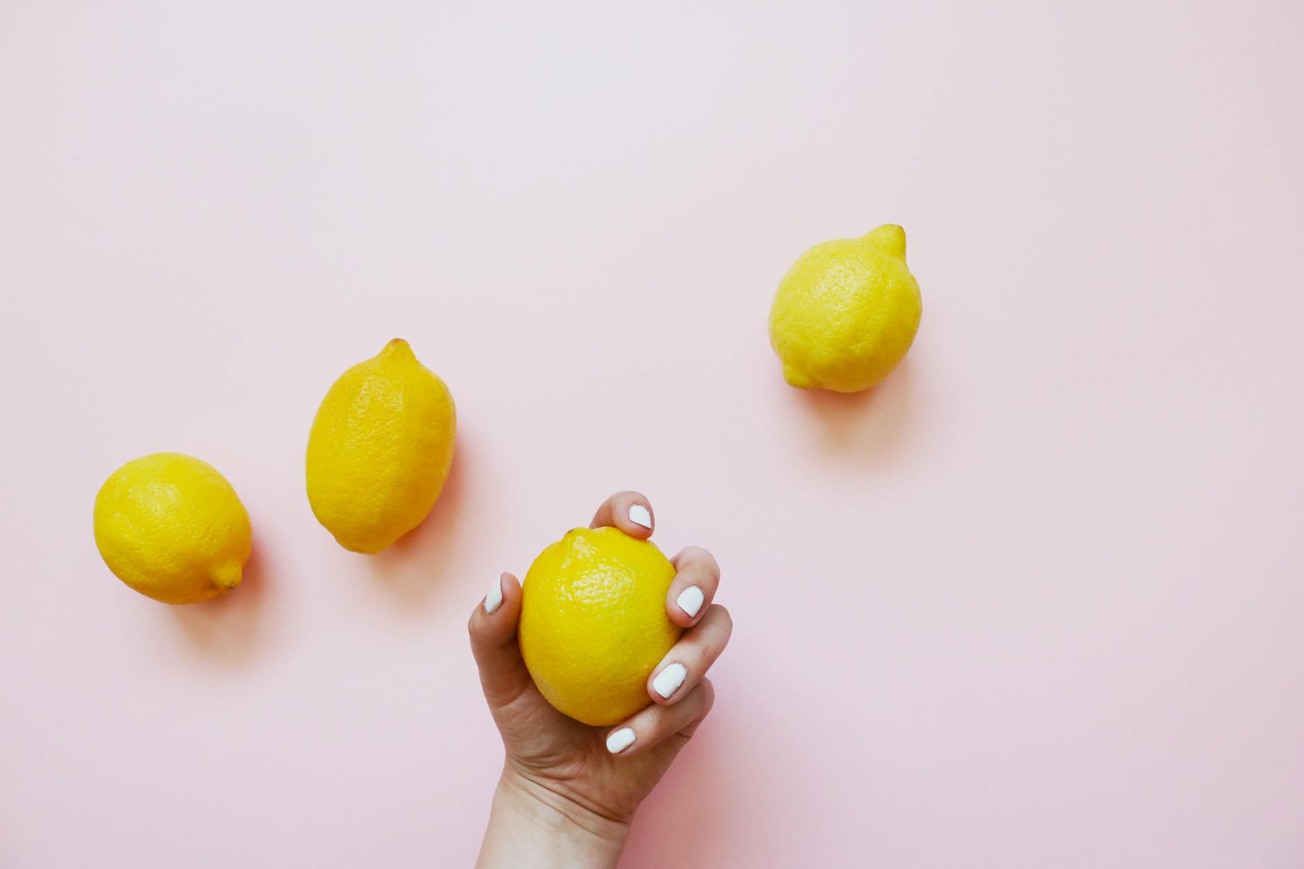 A hand holding an orange vibrator against a minimalistic purple backdrop, showcasing sensual touch