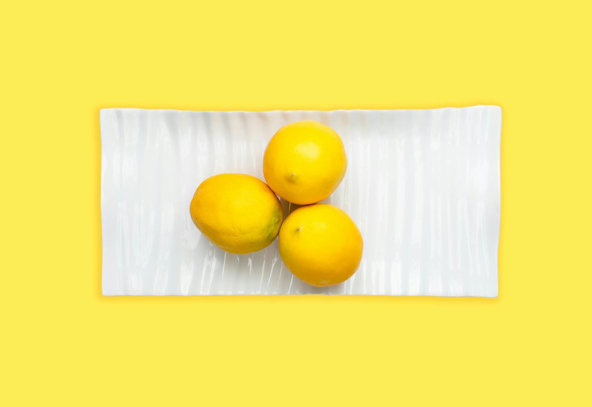 Fresh lemons on a white plate with a yellow background, symbolizing vitality and pleasure during midlife transitions