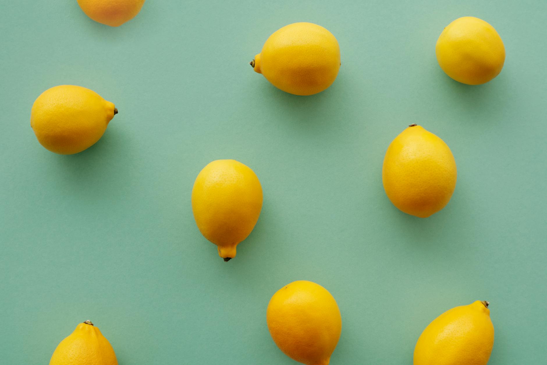 Bright yellow lemons arranged on a pastel green background, symbolizing freshness and the vibrant lemon sucker design