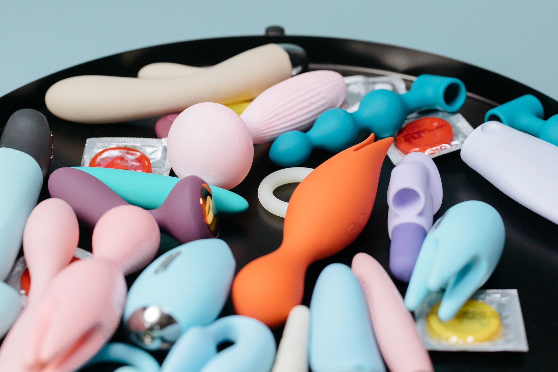A vibrant collection of various clitoral vibrators and toys on a black surface, featuring diverse shapes and colors