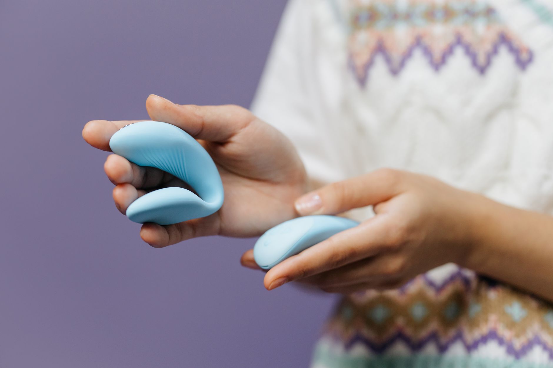 Hands holding a sleek lemon vibrator against a purple background, symbolizing self-care and anxiety relief
