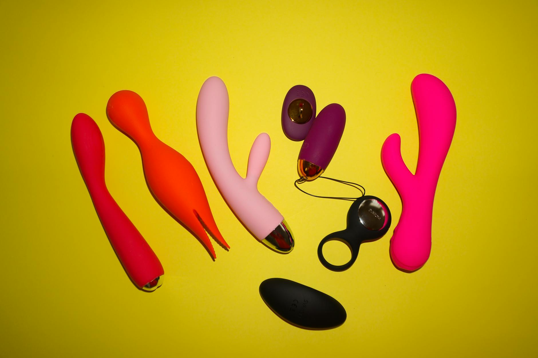 Colorful silicone vibrators arranged on a bright yellow background